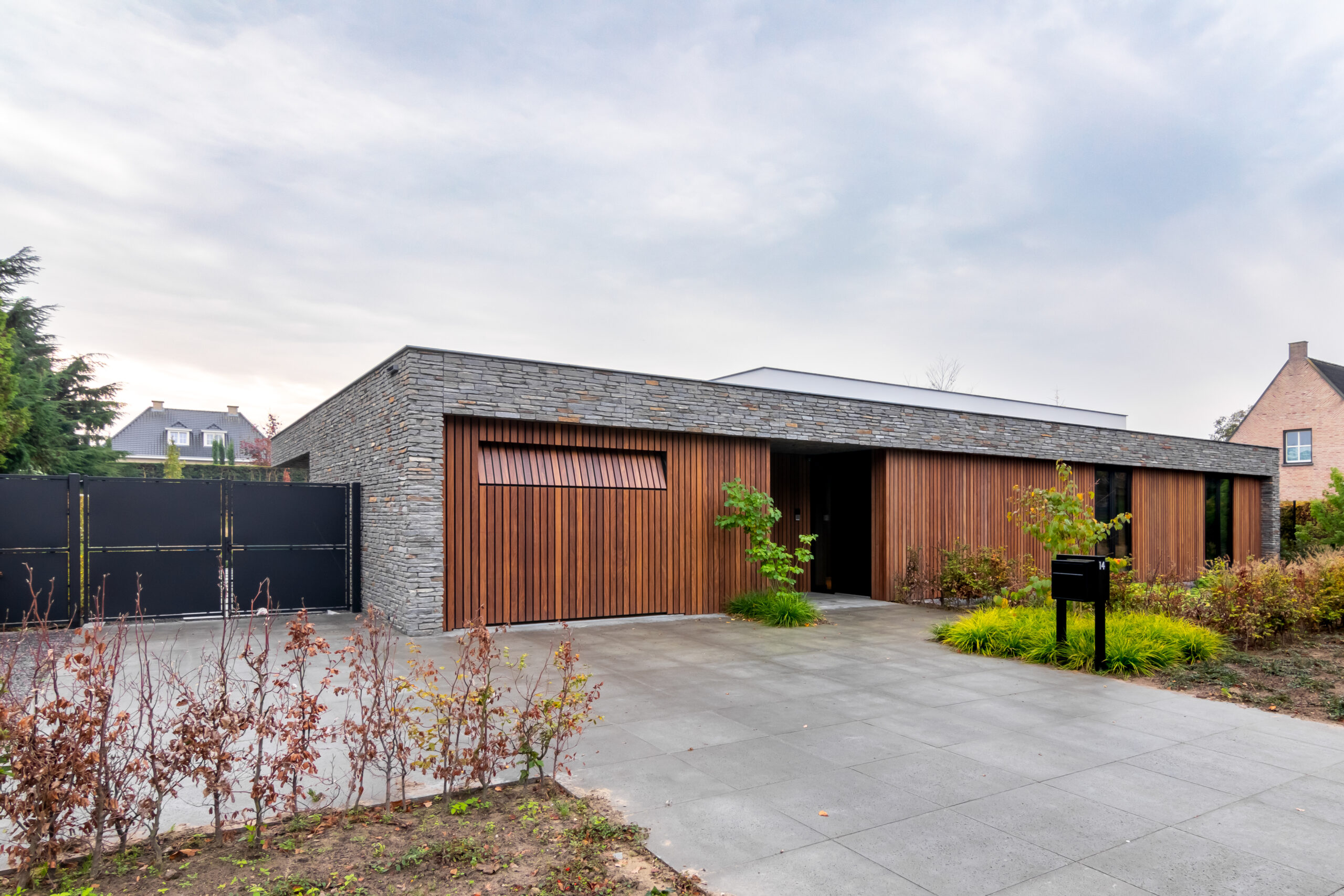 Nieuwbouw moderne bungalow, Haagse Beemden, Breda, Noord-Brabant, van Os Architecten, voorgevel met natuurstenen volume ingevuld met houten geveldelen.
